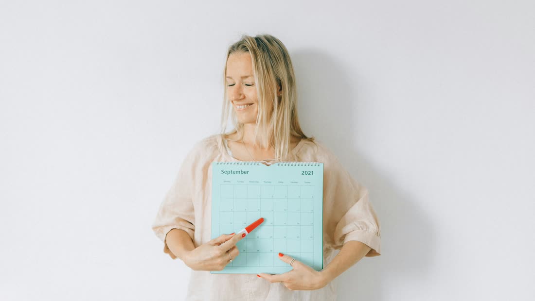 A person pointing at a marked date on a calendar