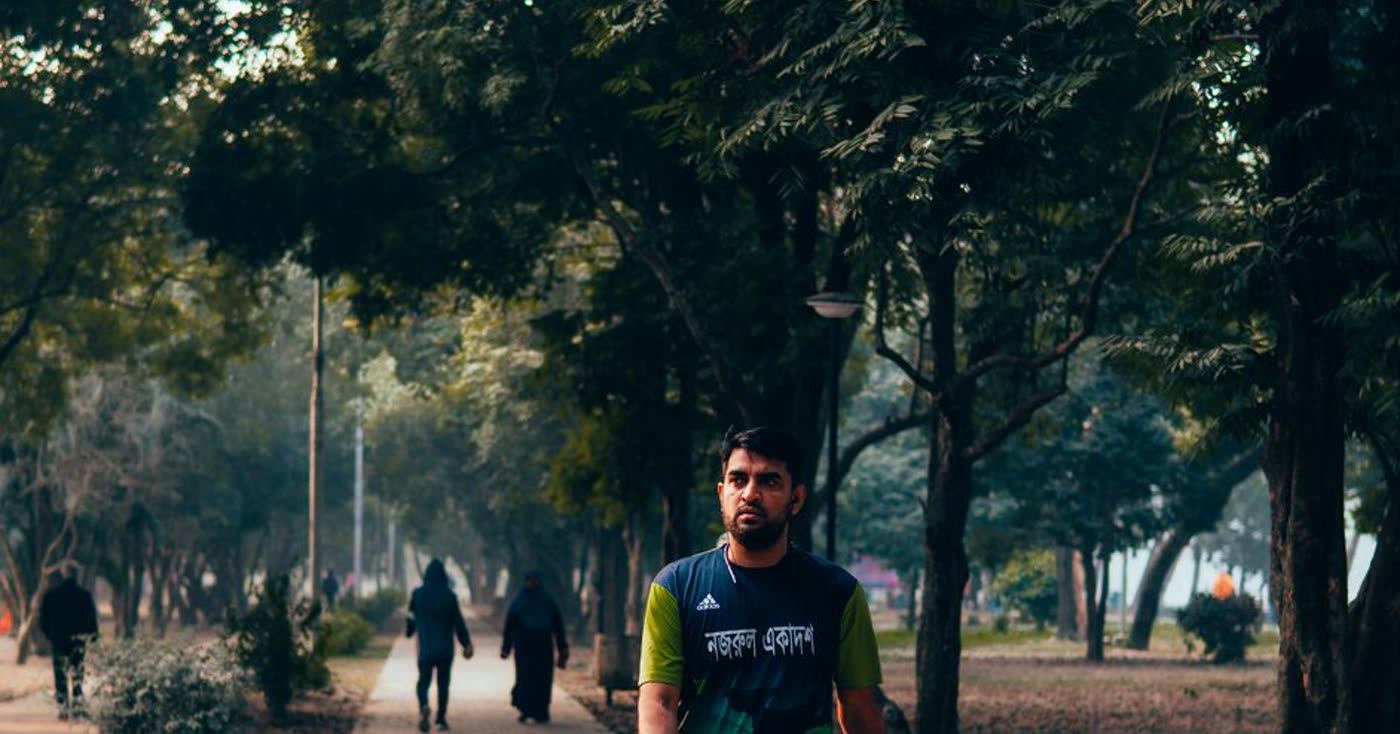 A person moving along a green park path for fresh air after quitting