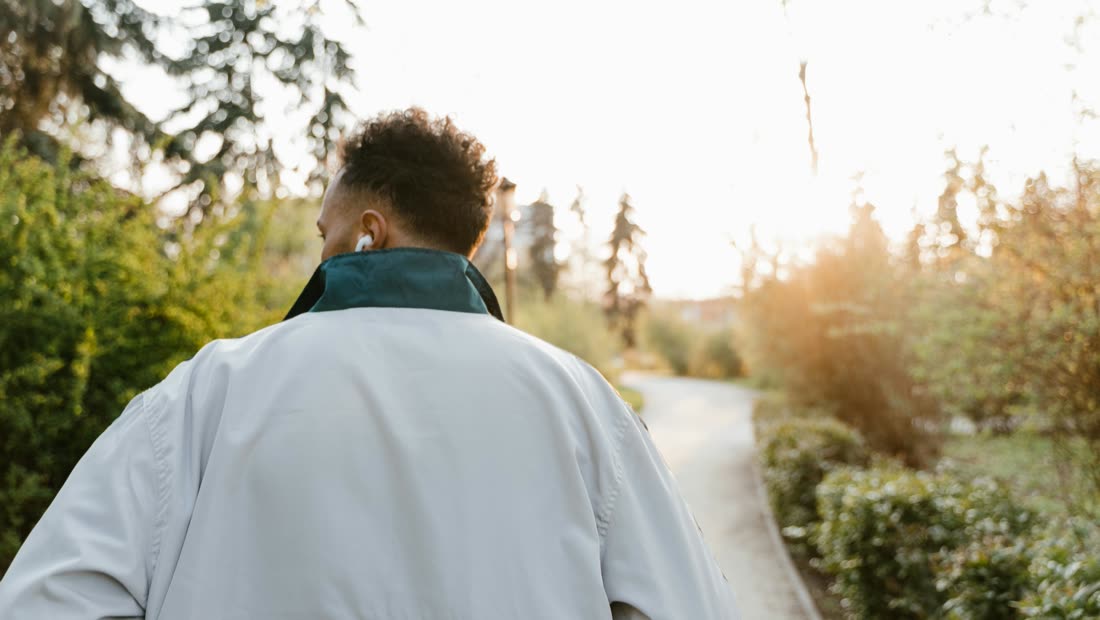 A person walking through a sunlit park