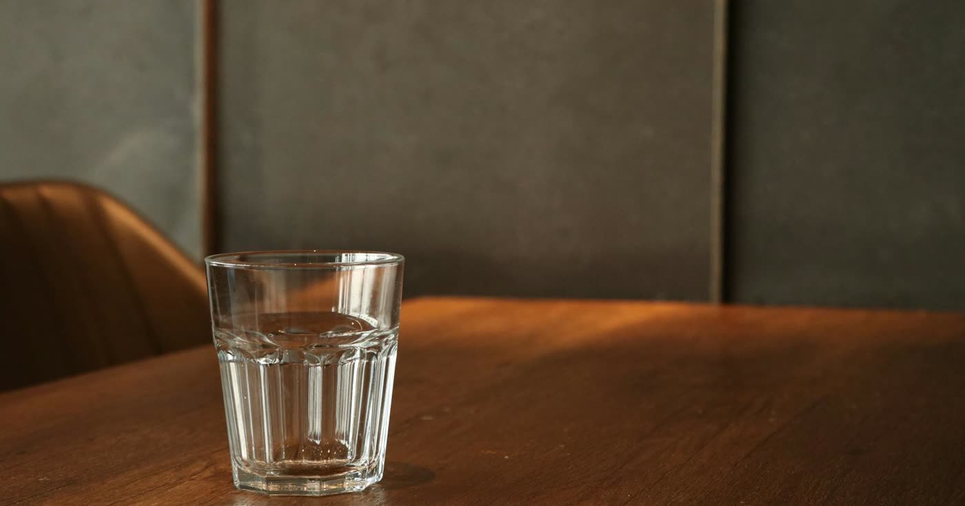 A minimalist glass of water on a wooden table for a five-minute craving reset