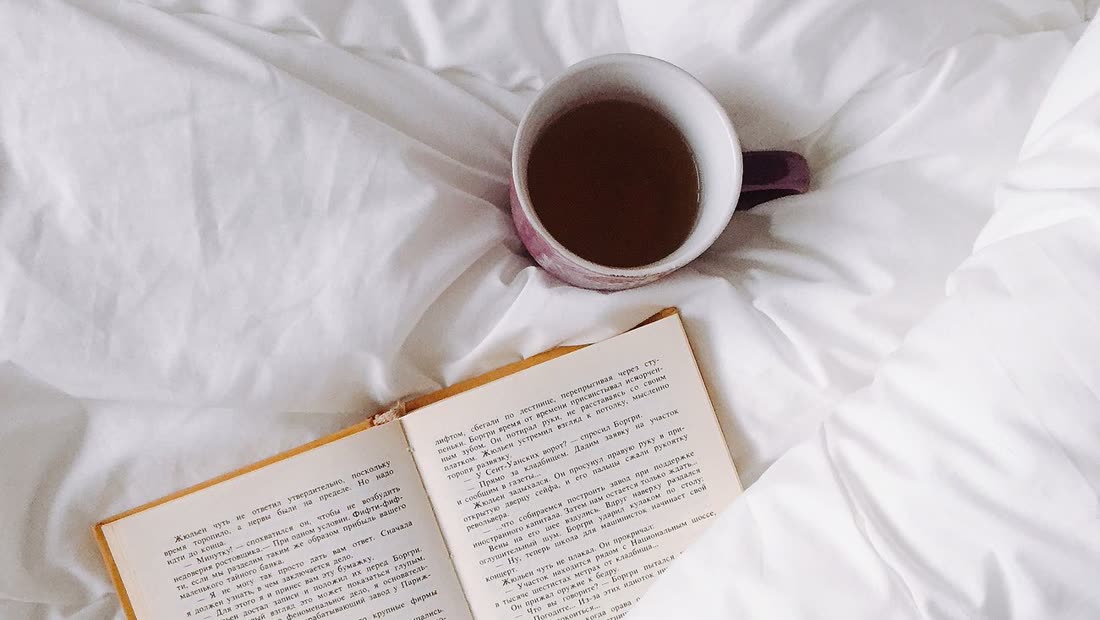 Books and tea beside a bed during a nighttime craving