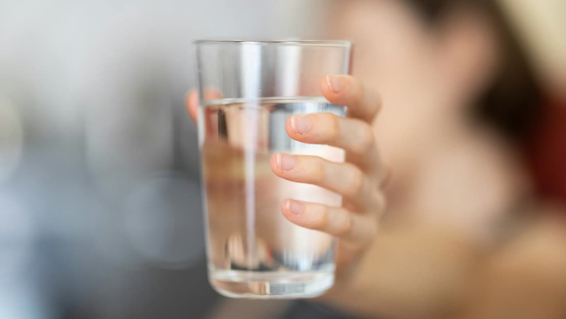 A hand holding a clear glass of water as a simple first-day craving replacement habit