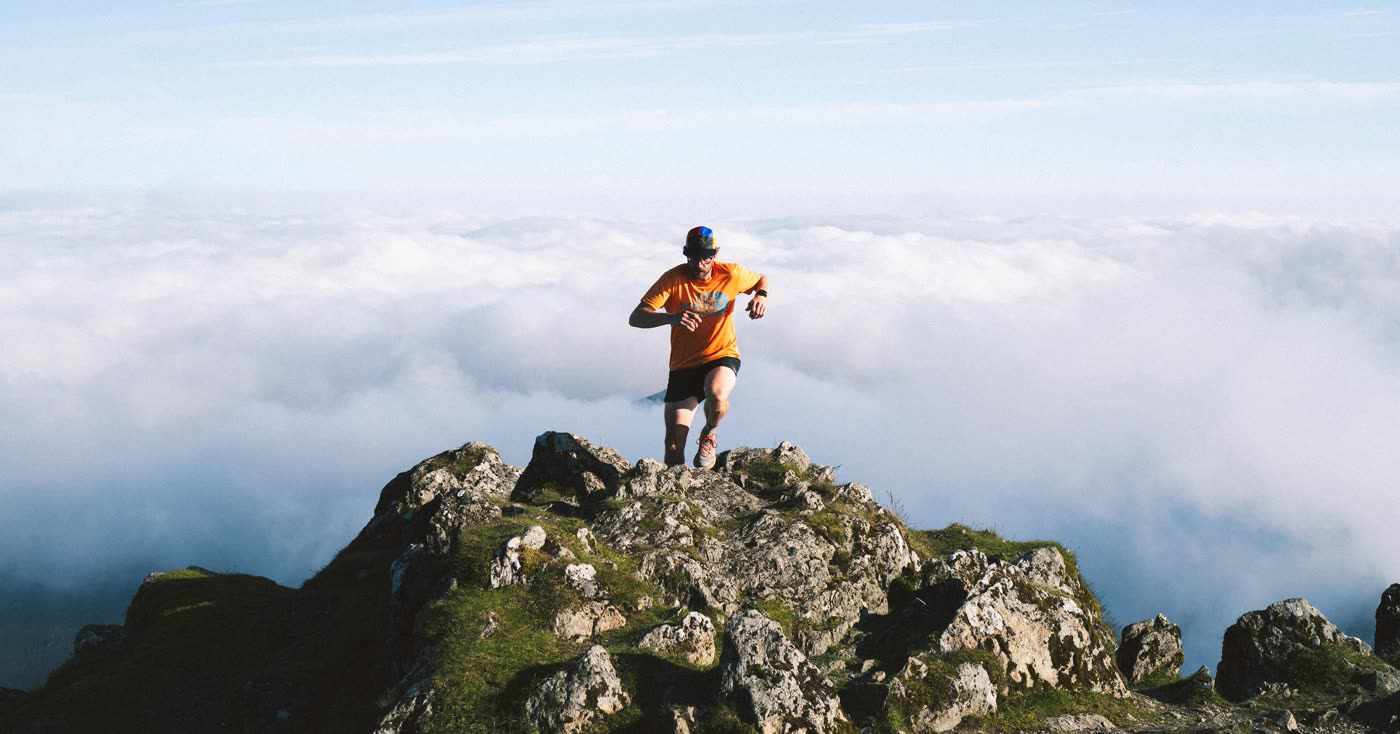 A runner on a mountain ridge above the clouds